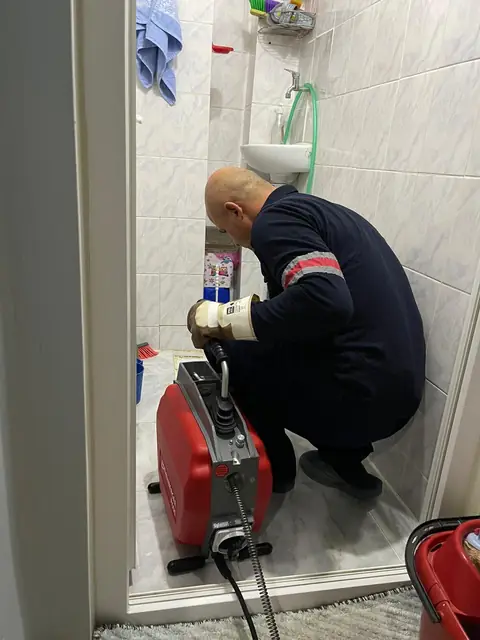 Teknisyen suyu yükselmiş bir klozetin gider ağzına spiral makinenin ucunu yerleştiriyor.