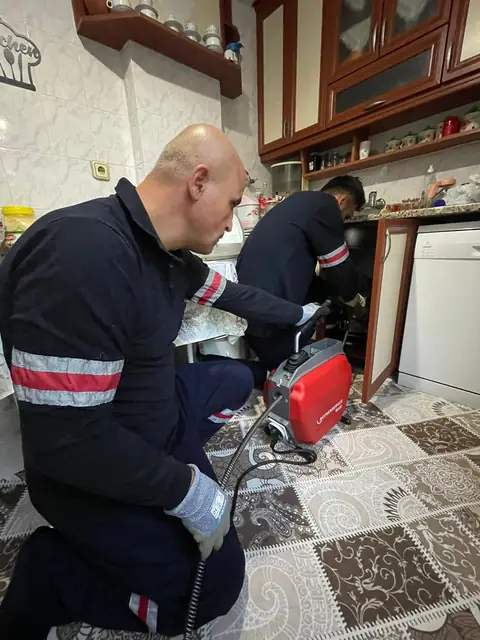 Mutfak tezgâhının altında bulaşık makinesi tahliye hortumunun sifona bağlandığı nokta kontrol ediliyor.