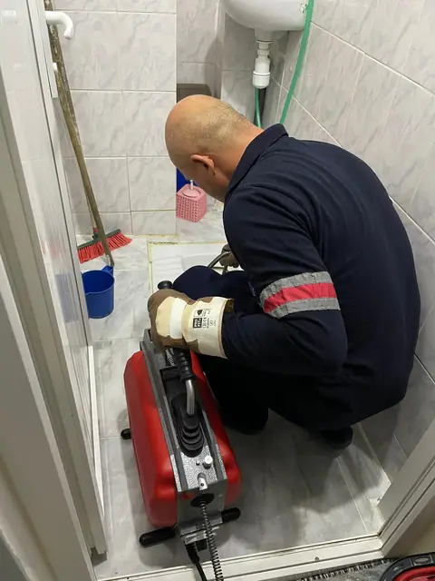 Banyodaki yer süzgecinin ızgarası kaldırılmış, içindeki koku önleyici hazne kontrol ediliyor.